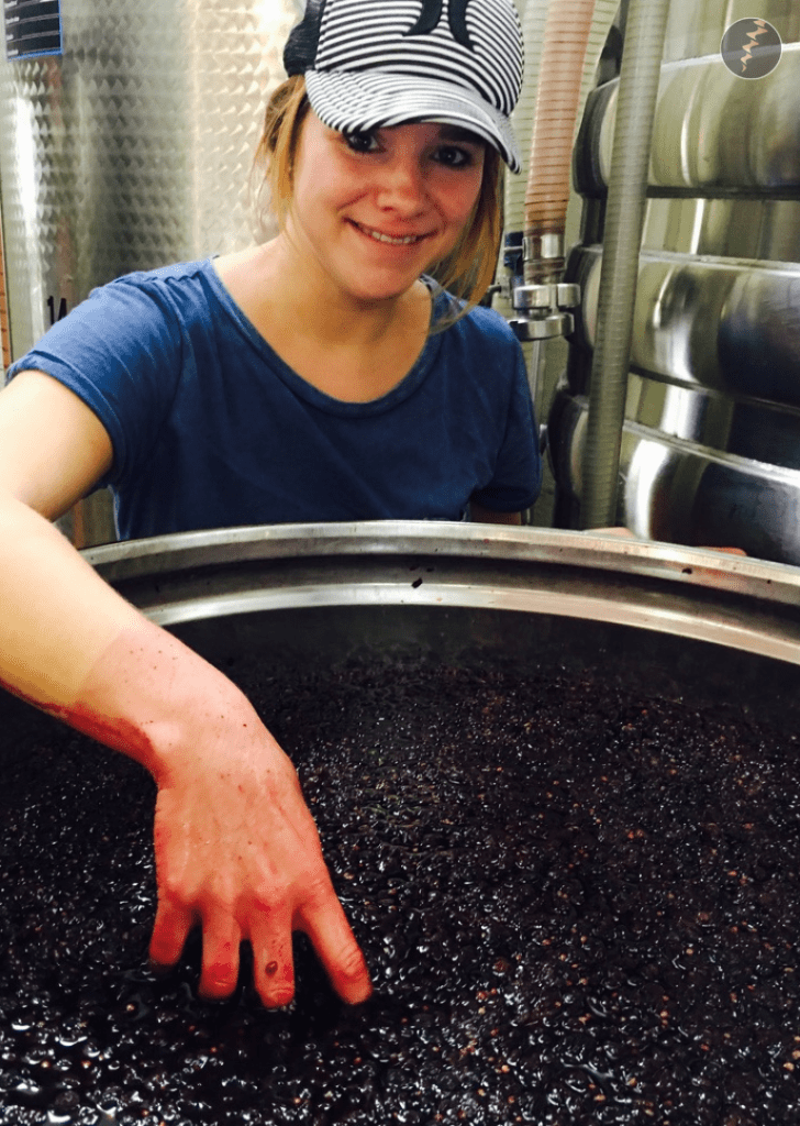 Lisa having her hands in a red wine fermentation tank